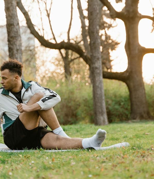 Athletic man stretching outdoors during sunrise for energy boost.